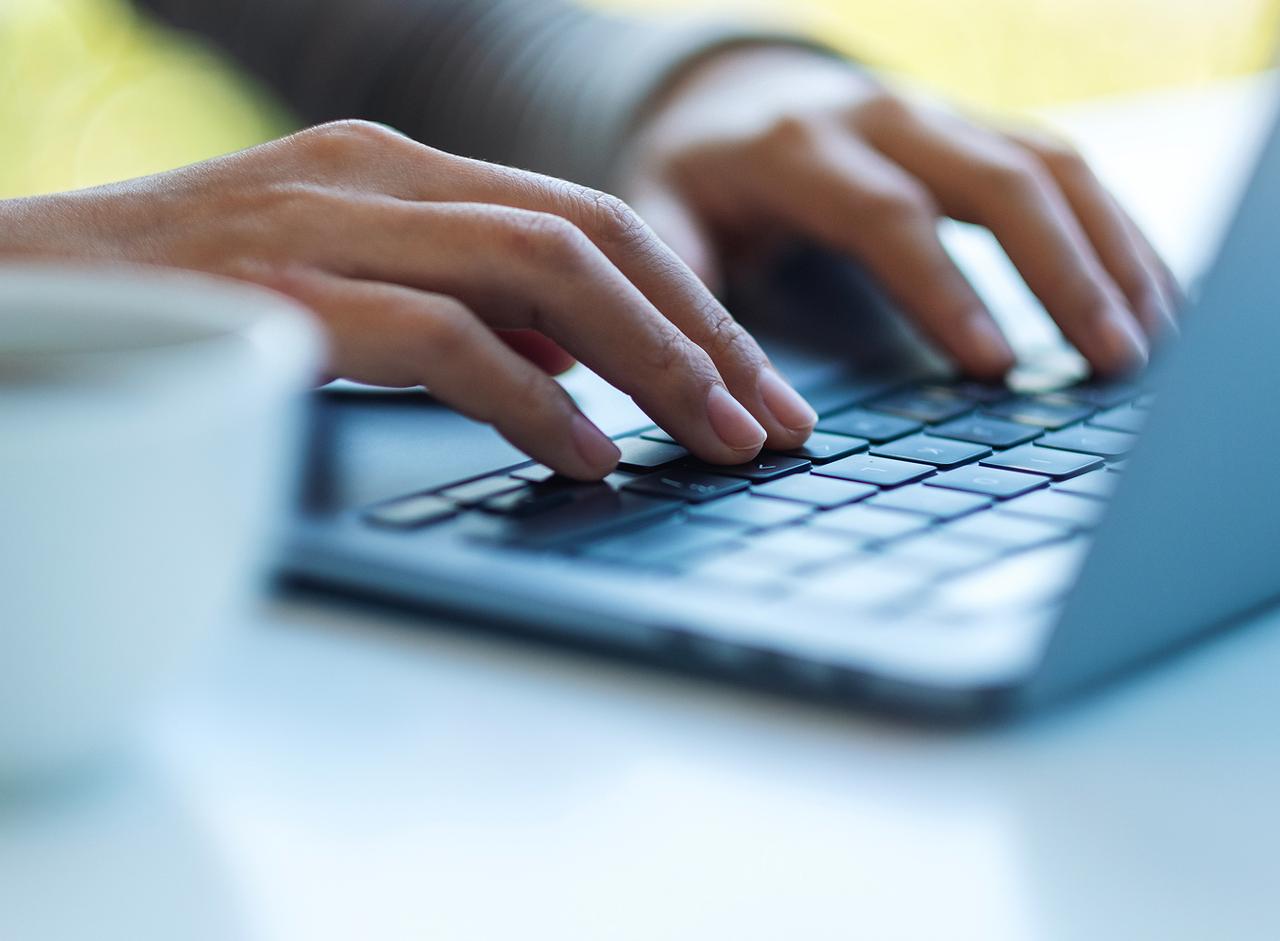 Hands typing on a laptop keyboard to submit an online print order.